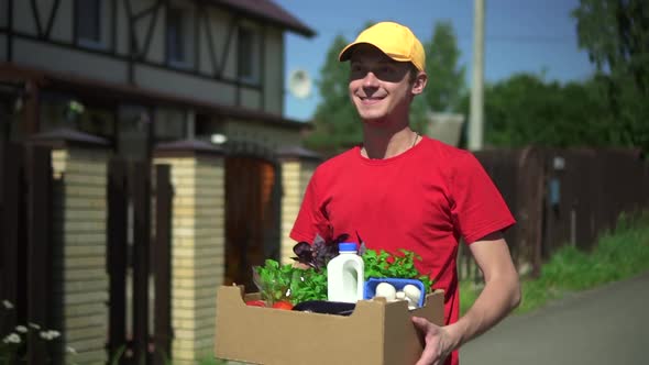 Young Man Deliver Walks on City Street and Holds Box of Food in His Hands Spbd