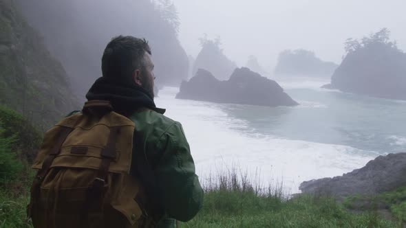 Back View of Handsome Man with Tourist Backpack Enjoying Cinematic Oregon Beach