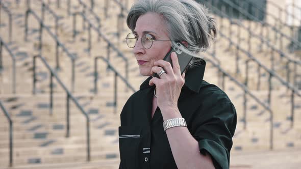 Grayhaired Mature Lady in Black Shirt Talking on the Phone During Lunch Break