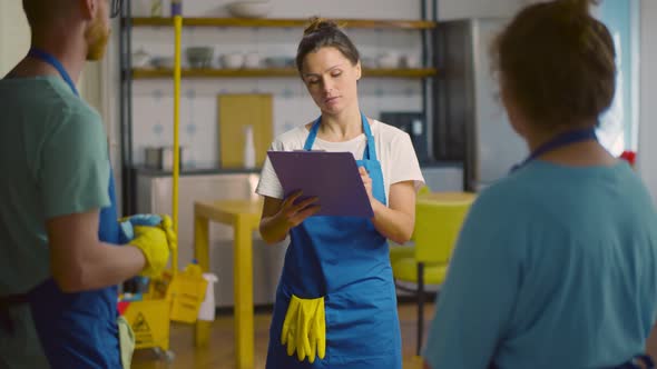 Team of Janitors Making Check List in Clipboard Working in Modern Apartment