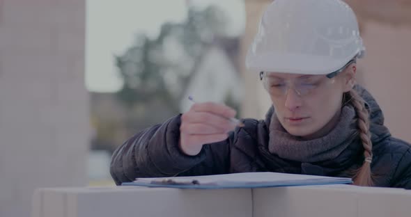 Confident Young Female Civil Engineer Drawing Blueprint at Site