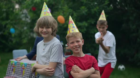 Positive Cauacsian Boys Crossing Hands Looking at Camera Standing Outdoors at Birthday Party