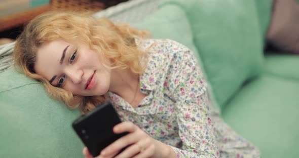 Coquette Woman Using Smartphone Sitting on Green Sofa