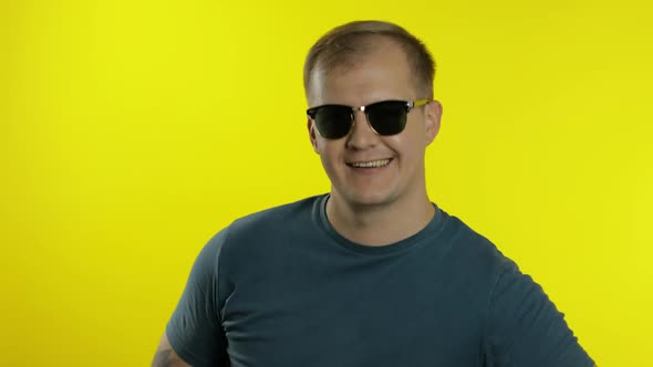 Portrait of Young Man Posing in T-shirt. Cool Handsome Guy Wears Sunglasses, Trying To Look Good