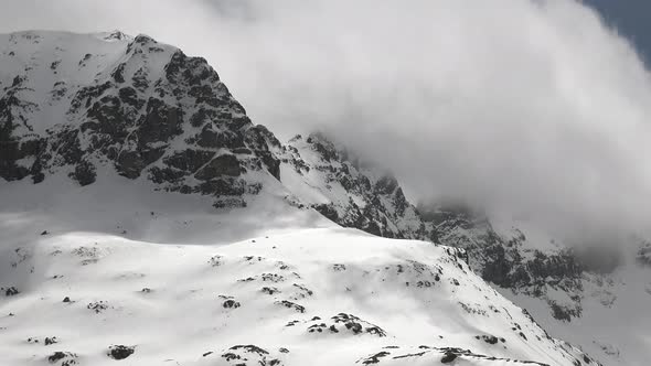 High Altitude Rocky Snowy Mountain Ridge in Winter Clouds