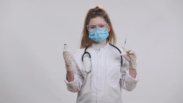 Confident Little Doctor in Covid Face Mask Holding Covid19 Vaccine Jab and Syringe Looking at Camera