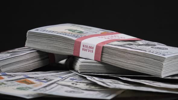 Bundles of Dollars Lying on a Pile of Money and Rotate on Black Background