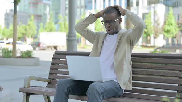 African Man Reacting to Loss on Laptop While Sitting Outdoor on Bench