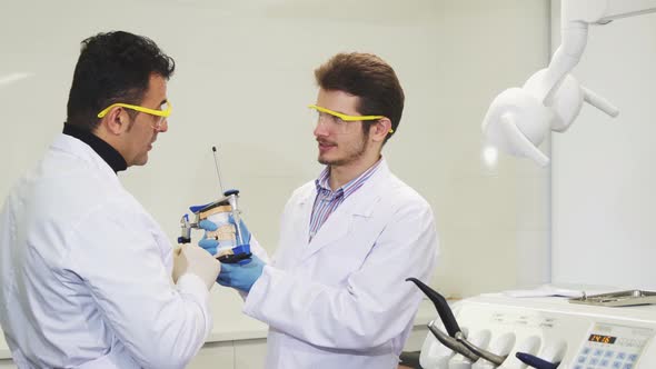 Young Male Dentist Working with His Colleague Examining Dental Mold