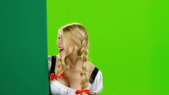 Girl in Bavarian Costume Shows Thumb From the Board. Oktoberfest. Green Screen