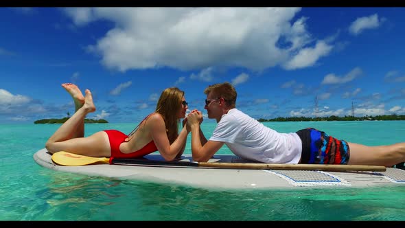 Boy and girl sunbathing on exotic lagoon beach wildlife by shallow lagoon and white sand background 