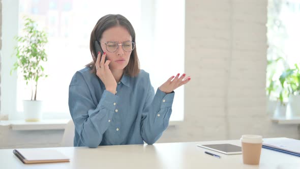 Angry Young Woman Talking on Phone in Office