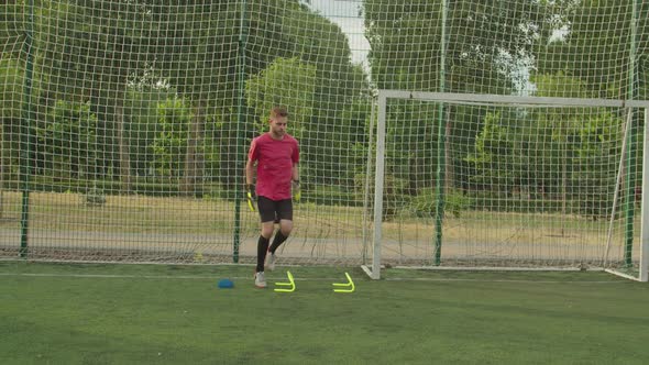 Male Soccer Goalie Performing Complex Training Catching Ball Outdoors