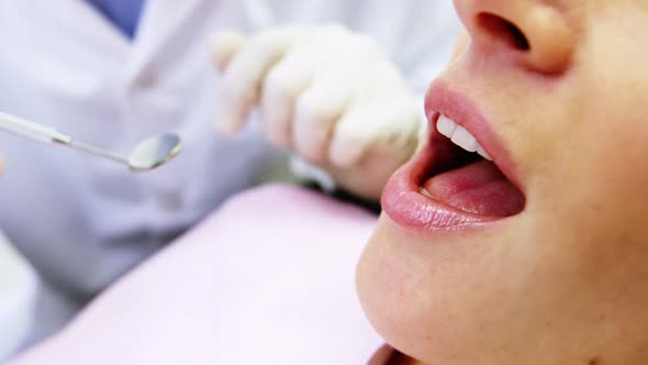 Dentist examining a female patient with tools