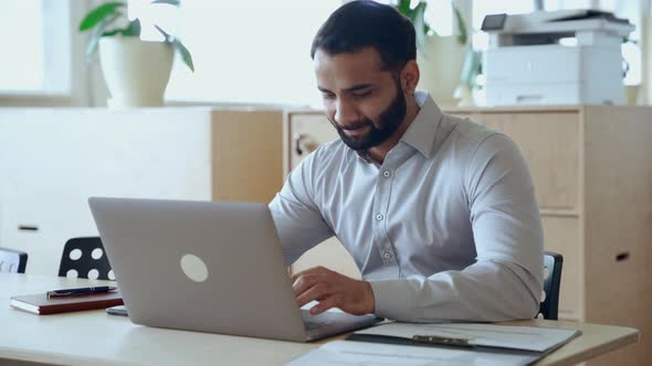 Indian Businessman Using Laptop Computer Working in Office Looking at Laptop