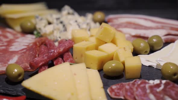 Closeup of Cutting Board with Sliced Salami, Crackers, Green Olives, Nuts and Berries and Assorted