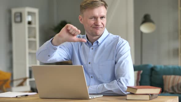 Thumbs Down By Businessman Looking at Camera at Work