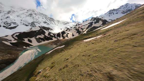 FPV Drone Shot Flying Over Sunny Valley Towards to Blue Lake and Snowy Alps