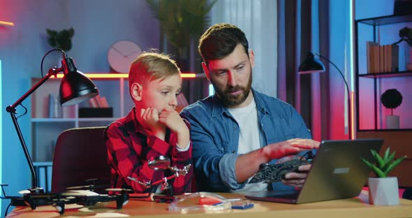 Father Talking with His Teen Son About Electronic Panel with Components and Reading Information