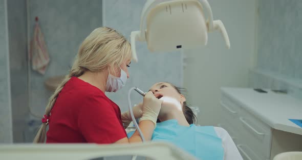 Beautiful Woman Dentist Performs Procedures for Oral Hygiene Removal of Plaque