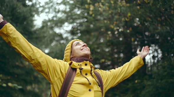 Portrait of Inspired Young Pretty Woman Hiker with Backpack Wearing Bright Yellow Raincoat and