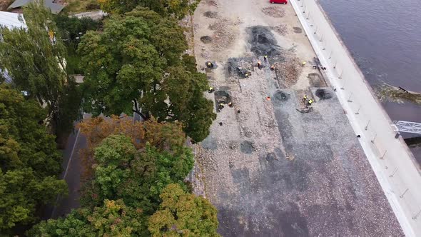 Workers working in archeological digsite on riverside in Kaunas city, aerial view