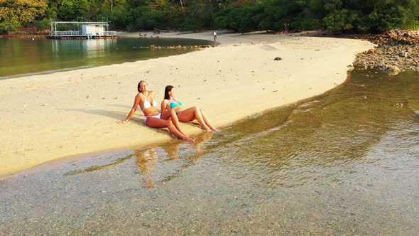 Beautiful ladies enjoying life on relaxing resort beach break by blue sea and white sandy background