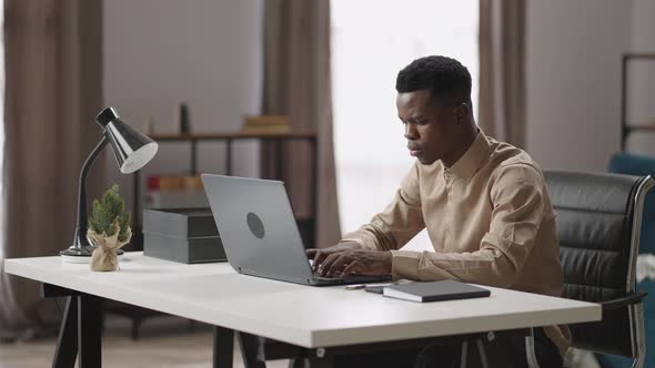 Black Man is Typing Message on Laptop Sending Email Working From Home During Pandemic Afroamerican