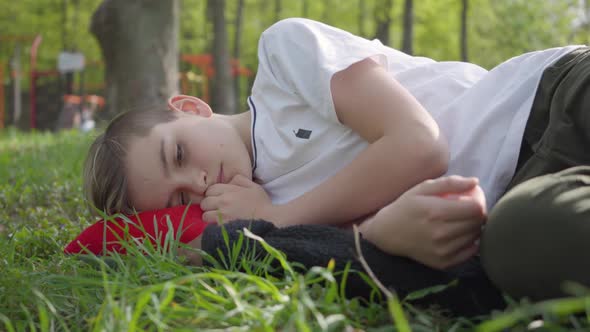 Portrait of a Cute Boy Lying on Green Grass in Spring Park. Outdoor Recreation