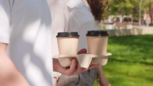 Unrecognizable Man and Woman with Takeaway Coffee Walking Together