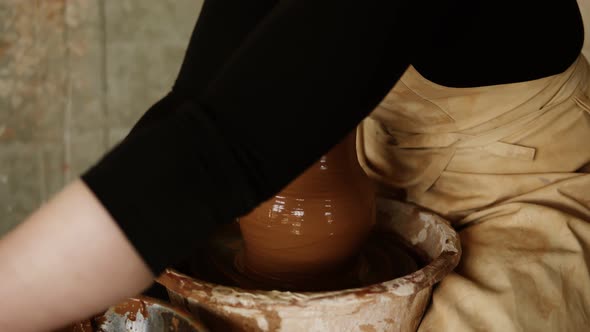 Female Potter Cuts Off Excess Clay on the Top of the Vase