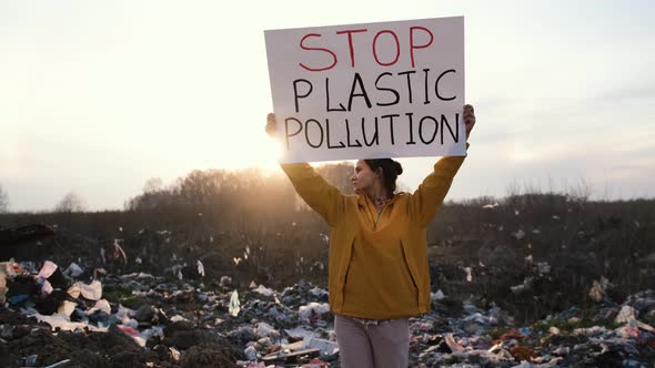 Portrait of a Young European Girl in a Huge Garbage Dump with Posters for Environmental Activists