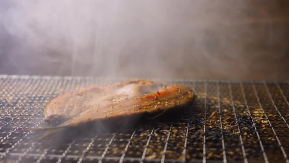 Smoking Ide Fish Steak with Hot Steam on Grid Lying on Chips