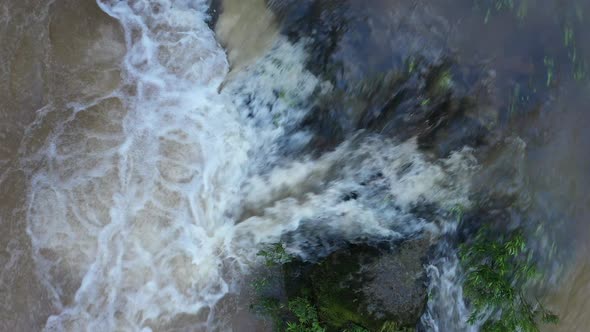 Clear water that runs over rocks and turning in a brown turbulent stream with foam on top