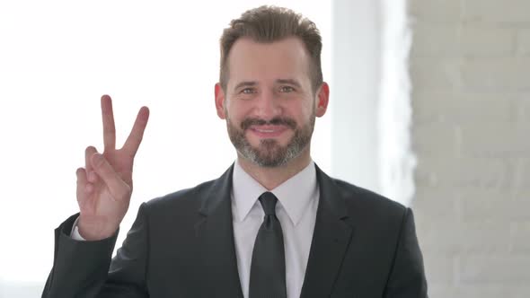 Middle Aged Businessman Showing Victory Sign with Finger