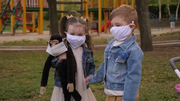 Two Small Cute Children in Medical Protective Masks Walking in the Park.COVID-19