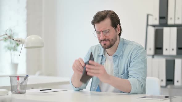 Young Man Checking Empty Wallet at Work