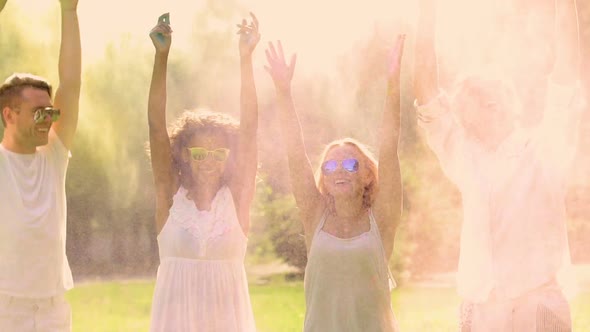 Happy Young Dancing Friends Spraying Powder Paint at Music Festival, Holi