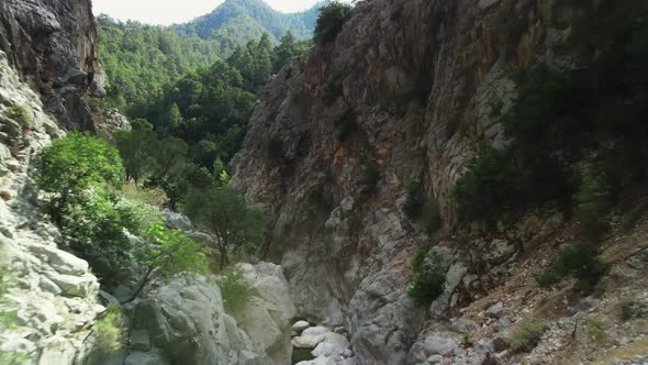 Landscape of High Rocky Mountains and Gorge Between Them with Stream of Water on the Bottom