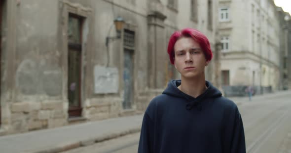 Portrait of Young Hipster Guy in Dark Hoodie Looking To Camera. Crop View of Millennial Man with Red