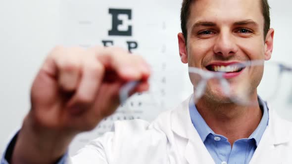 Smiling optometrist holding spectacles