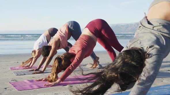 Group of diverse female friends practicing yoga at the beach