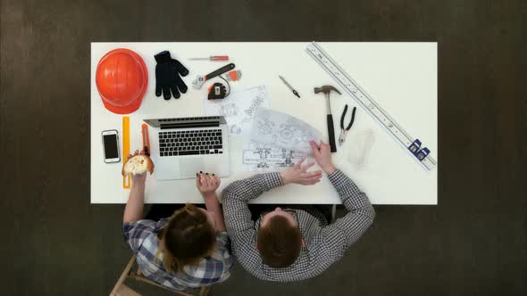 Female Architect Discussing Drawing with Her Coworker While Eating Lunch and Typing