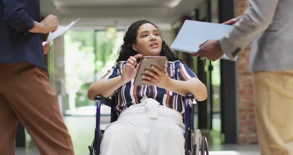 Smiling diverse business people with colleague in wheelchair talking in modern office