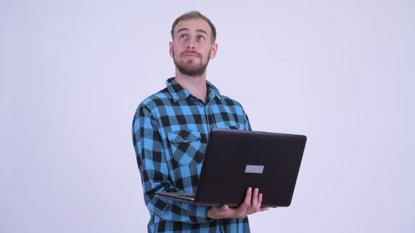 Happy Bearded Hipster Man Thinking While Using Laptop