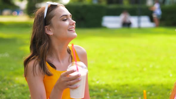 Teenage Girls Drink Milk Shakes at Picnic in Park