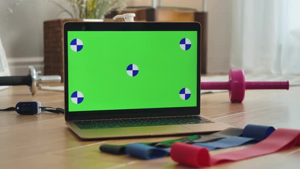 Close-up of Chromakey Laptop Screen with Female Hand Taking Resistance Bands Lying on the Floor