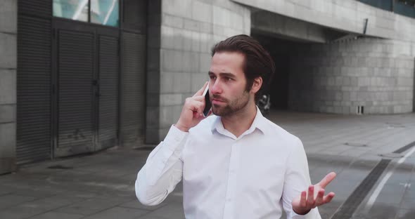 Handsome Bearded Startup Businessman in White Shirt Talking on the Phone Walking Down the Street to