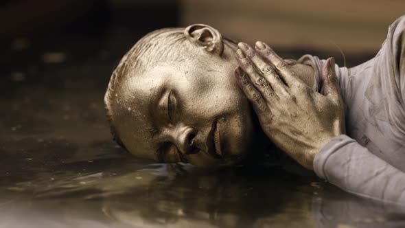 Young Woman Is Covered Golden Paint in Water Closeup of Face and Hair Dyed By Shiny Pigment