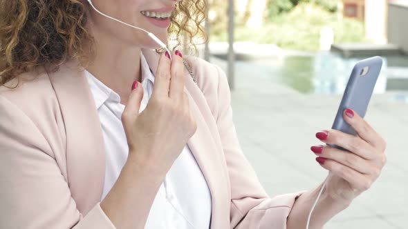 Portrait of a Business Woman Able to Work on a City Street with a Phone and Headphones